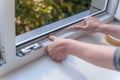 a woman glues a sealing rubber tape on a window in a living room