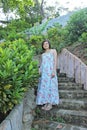 A woman go down stair with green tree along the upstair