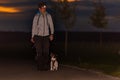 Woman goes with a dog walking in the autumn at night with heard torch - jack russell terrier