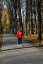 A woman goes in for sports in a city park. The woman is engaged in Scandinavian walking.