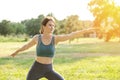 A woman goes in for sports in nature. Sportive young woman practices yoga in the park. Woman athlete performs stretching
