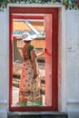 A woman going out of the door, back side view. Tourists wlaking on territory of Grand Palace. Local people of Asia.