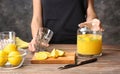 Woman is going to pour fresh lemon juice into glass at table