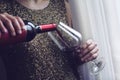 Woman with gold spangle dress pouring red wine into a glass