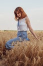 Woman with golden brown hair walks through beautiful golden wheat field, hot summer season. Happy girl enjoying life Royalty Free Stock Photo