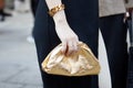 Woman with golden metallic bag and bracelet before Bottega Veneta fashion show, Milan Fashion