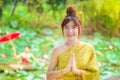 Woman in the golden Thai dress is good morning in the lotus garden