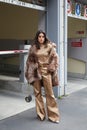 Woman with golden trousers, beige shirt and brown fur coat before fashion Albino Teodoro show, Milan Fashion
