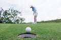 woman golf player putting successfully ball on green, selective focus blur background and clear sky Royalty Free Stock Photo