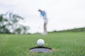 woman golf player putting successfully ball on green, selective focus blur background and clear sky Royalty Free Stock Photo