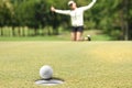 Woman golfer cheering after a golf ball on green