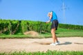 Woman golfer hitting a ball on a bunker, with vineyard in the background at Zlati Gric in Slovenia Royalty Free Stock Photo