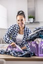 Woman in good mood smiles and irons clothes with a purple iron and clothes in a purple plastic basket Royalty Free Stock Photo