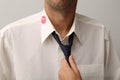 Woman grabbing her husband by tie due lipstick kiss mark on his shirt, closeup