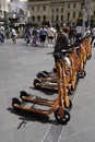 Woman grabs an electric kick scooter from a row of shared or e-scooters and helmets
