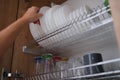 Woman graceful hand takes out clean plate from cupboard