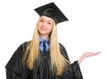 Woman in graduation gown presenting on empty hand