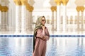 Woman in grand mosque of Sheikh Zayed in front of water. Islamic decor. Female tourist in muslim country.