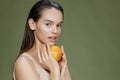 woman grapefruit in hands posing clean skin green background