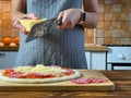 Woman is grating cheese for Pepperoni pizza Royalty Free Stock Photo