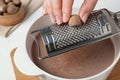 Woman grating nutmeg into cacao at table, closeup Royalty Free Stock Photo