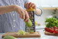 Woman grating zucchini at kitchen table, closeup Royalty Free Stock Photo