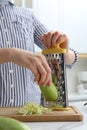 Woman grating zucchini at kitchen table, closeup Royalty Free Stock Photo