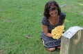 Woman at grave stone with yellow flowers. Royalty Free Stock Photo