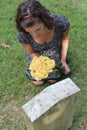 Woman at grave stone with yellow flowers. Royalty Free Stock Photo