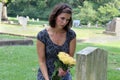 Woman at grave stone with yellow flowers. Royalty Free Stock Photo