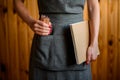 Woman in gray apron holds pack of colored pencils and sketchbook