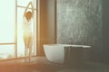 Woman in gray bathroom corner with tub Royalty Free Stock Photo