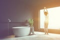 Woman in gray bathroom corner, white tub Royalty Free Stock Photo