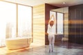 Woman in gray bathroom, tub and shower Royalty Free Stock Photo