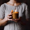 Woman in gray dress holding burning candle, design and branding ready candle jar mockup with female hands, no face Royalty Free Stock Photo