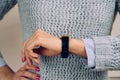 Woman in a gray sweater checks the time on a wrist watch close-up