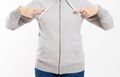 Woman in gray sweatshirt pointing with two hands, girl in hoodie sweater on light background. Space for design mock up Royalty Free Stock Photo