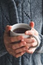 Woman wearing a gray woolly cardigan holding a mug of tea