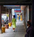 Woman with green dress and face mask walking down sidewalk.