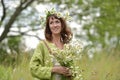 Woman in a green dress with a wreath of daisies in her hair and a bouquet of daisies in her hands Royalty Free Stock Photo