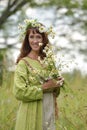 Woman in a green dress with a wreath of daisies in her hair and a bouquet of daisies in her hands Royalty Free Stock Photo