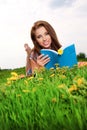 Woman on green field and reads book.