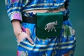 Woman with green satin bag with silver elephant and blue silk trousers and shirt before Emporio Armani