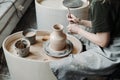 woman in green shirt making a clay pot using the potter& x27;s wheel. making a caly pot