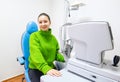 a woman in a green sweater is sitting in a blue chair in front of a machine