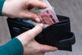 A woman green turtleneck holds a black leather wallet in her hands. Royalty Free Stock Photo