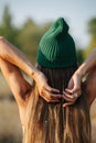 Woman in a green watch cap stretching, enjoying views on a countryside