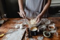 a woman prepares dough with wooden shovel in a glass bowl on a wooden table. There are other products on the table Royalty Free Stock Photo