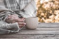 Woman in grey plaid with a mug of beverage in early morning. Atmospheric autumn composition. Sunday relaxing, memories