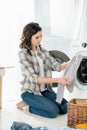 woman in grey shirt and jeans holding clothes near washer Royalty Free Stock Photo